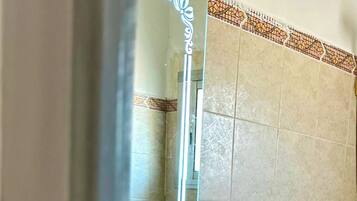 A bathroom with a sink, mirror, and a shelf with a bottle.