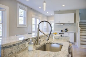A kitchen with a granite countertop, stainless steel sink, and white cabinets. - Cozy Fountain Square Retreat Just Steps from Downtown Indianapolis (Indianapolis)
