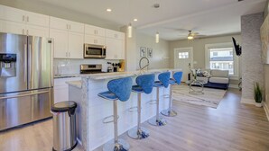 A modern kitchen with stainless steel appliances, a bar area with blue bar stools, and a living area with a sofa and a coffee table. - Cozy Fountain Square Retreat Just Steps from Downtown Indianapolis (Indianapolis)