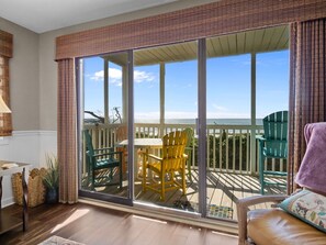 Varanda com vista para o oceano, com uma mesa e cadeiras.