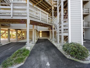 A covered parking area with a central pathway marked with the number 4, surrounded by wooden structures and greenery. - Breakers A-4 | Ocean Views, Pools & Beach Access (Pine Knoll Shores)