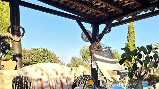Ein Sitzbereich im Freien mit einer Holzhütte, einer gepolsterten Bank und einer Vogelstatue.