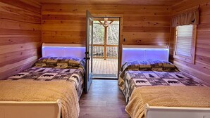A cabin room with two beds, wooden walls, a ceiling fan, and a door leading outside. - Blue Jay Riverfront cozy cabin along the Nottley River in Murphy, North Carolina (Murphy)