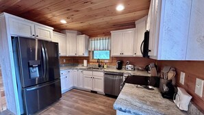 A modern kitchen with white cabinets, stainless steel appliances, and a wooden ceiling. - Blue Jay Riverfront cozy cabin along the Nottley River in Murphy, North Carolina (Murphy)