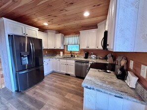 A modern kitchen with white cabinets, stainless steel appliances, and a wooden ceiling. - Blue Jay Riverfront cozy cabin along the Nottley River in Murphy, North Carolina (Murphy)