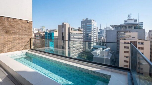 Una piscina al terrat amb vista a la ciutat, envoltada d'edificis moderns.