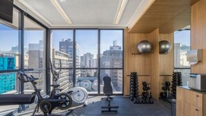 Un gimnàs modern amb equipament d'exercici, grans finestres i vista a la ciutat.