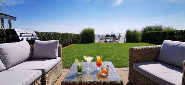 Une terrasse avec des meubles en osier, un barbecue et une table avec des boissons.