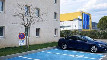 A parking area with blue handicapped parking spaces, a no parking sign, and a building with multiple windows.