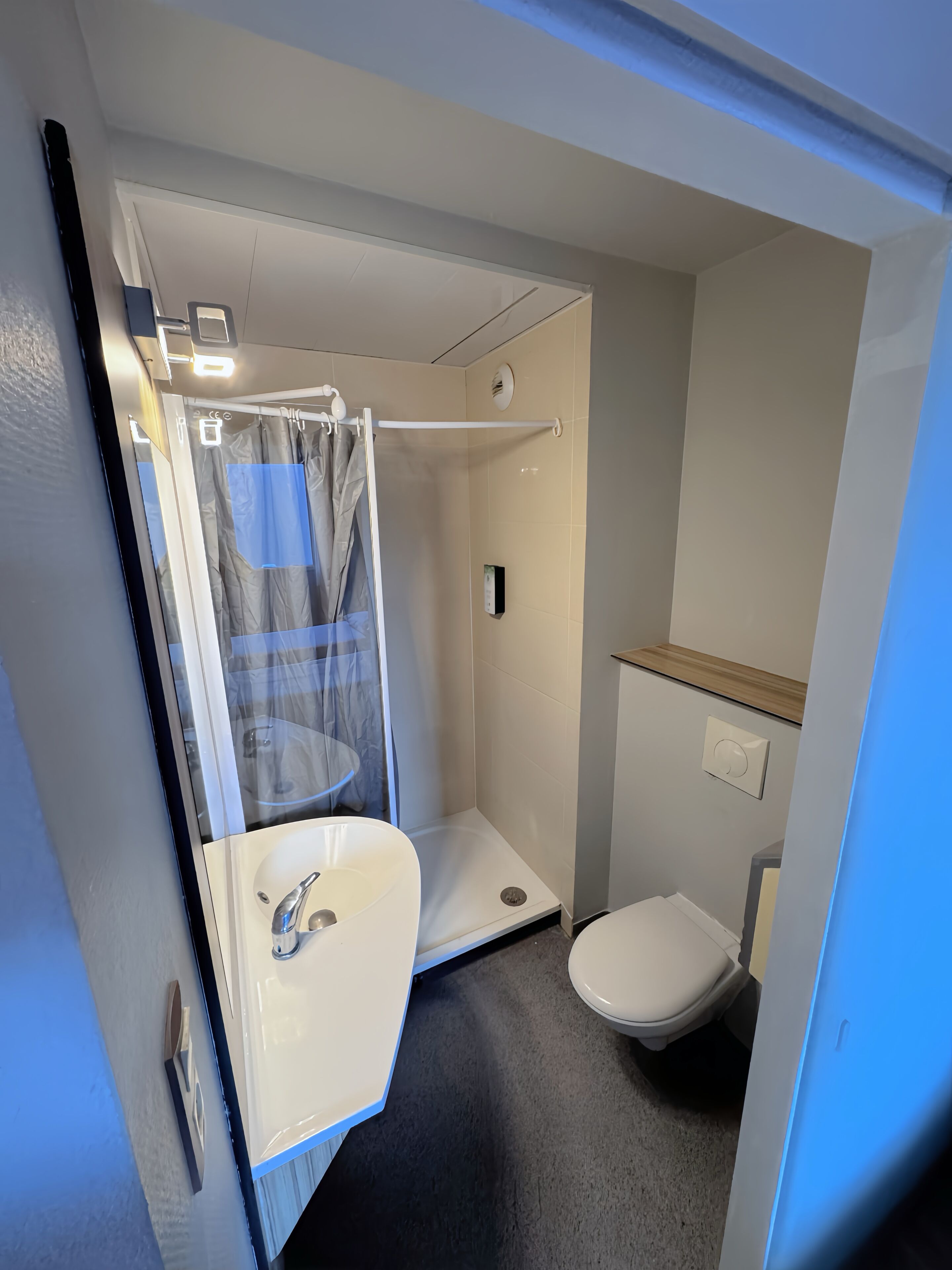 Un baño pequeño con ducha, inodoro y lavamanos.