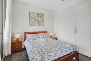 A bedroom with a bed, nightstands, a wardrobe, and a painting on the wall. - Lux 2BR apartment in Darling Harbour with Balcony Spa (Ultimo)