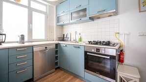 A modern kitchen with blue cabinets, a Bosch dishwasher, a Bosch oven, and a window providing natural light. - Unique 4-Level Home in the Heart of Beşiktaş (Istanbul)