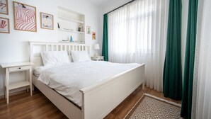 A bedroom with a bed, bedside tables, a nightstand, a shelf with books and decorative items, and a window with curtains. - Unique 4-Level Home in the Heart of Beşiktaş (Istanbul)