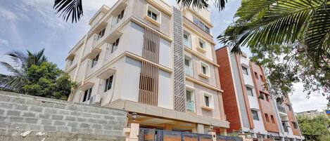 A multi-story residential building with a modern design, featuring balconies and large windows.