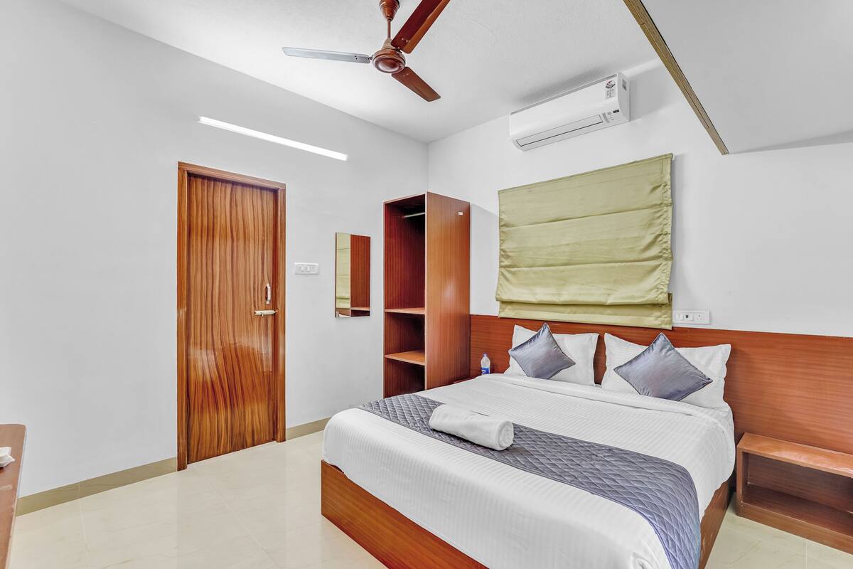 Ein Hotelzimmer mit einem hölzernen Bett, einem Deckenventilator, einer Klimaanlage, einem Holzschrank und einem Nachttisch.