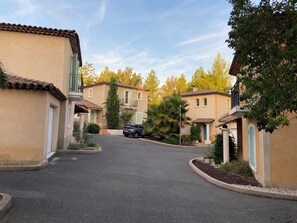 Une rue résidentielle bordée de maisons aux toits en tuiles et aux murs de couleur claire.