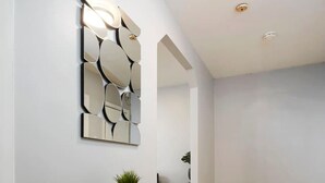 Ein zeitgemäßer Flur mit einem Holztischchen, einem Spiegel und einem Blumentopf.
