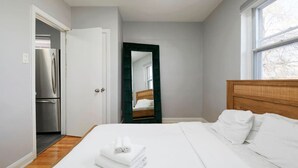 Ein Schlafzimmer mit Bett, Spiegel, Kleiderschrank und Fenster.