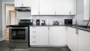 Eine moderne Küche mit weißen Schränken, einem Edelstahlbackofen und einer Kaffeemaschine.