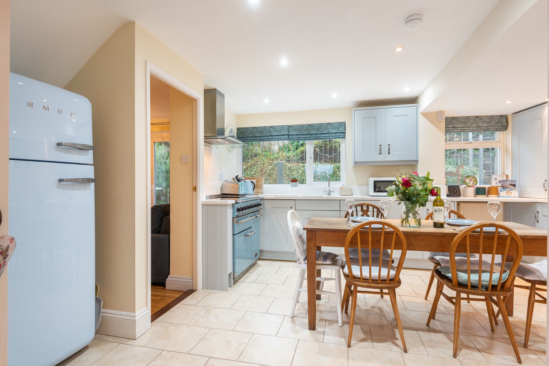 A compact kitchen with a refrigerator, stove, and dining area with chairs and a table.
