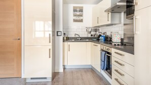 Uma cozinha moderna com armários claros, um exaustor de aço inoxidável e uma parede de proteção atrás da bancada.