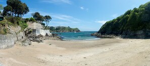 A beach with a stone wall, trees, and a view of the sea. - Zephyr - One Bedroom Apartment, Sleeps 2 (Fowey)
