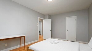 Ein Schlafzimmer mit einem hölzernen Bett, einem weißen Nachttisch und einem weißen Kleiderschrank.