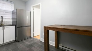 Eine Küche mit einem Edelstahl-Kühlschrank, weißen Schränken und einem Holztisch.