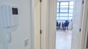 Un couloir avec un thermostat au mur, qui mène à un coin repas comprenant une table et des chaises.