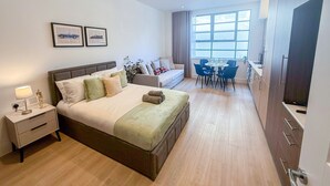 Une chambre d’hôtel moderne dotée d’un grand lit, d’un canapé, d’une table à manger avec des chaises et d’un coin cuisine.