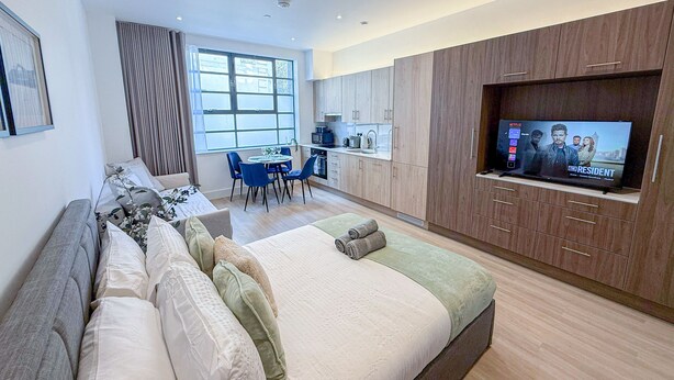 Une chambre d’hôtel moderne dotée d’un grand lit, d’une télévision, d’un coin repas et d’une kitchenette.