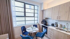 Une cuisine compacte avec un coin repas, comprenant une table ronde, quatre chaises et des appareils électroménagers modernes.