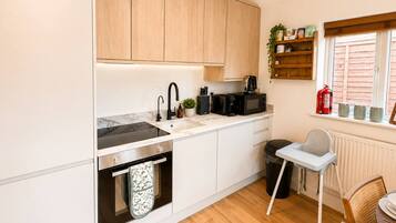 A compact kitchen with a sink, microwave, and a small dining area with a chair and table.