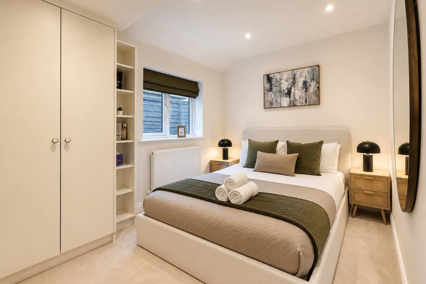 A bedroom with a bed, bedside tables, a wardrobe, a window with blinds, and a painting on the wall.