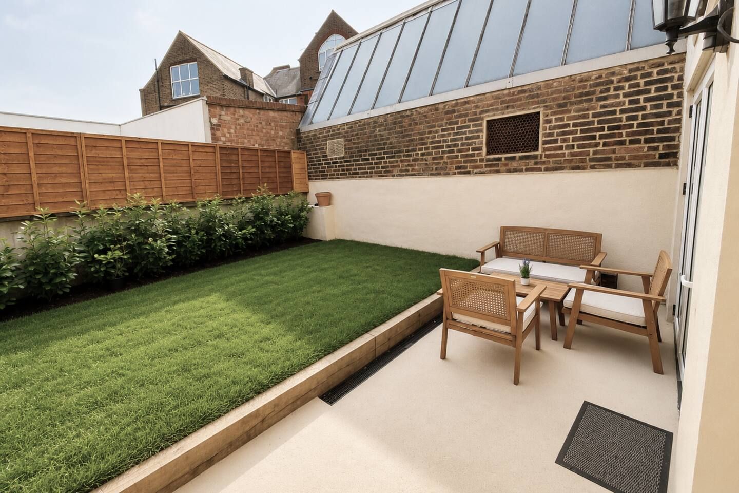A backyard with a well-maintained lawn, a wooden fence, and a patio area with a table and chairs.