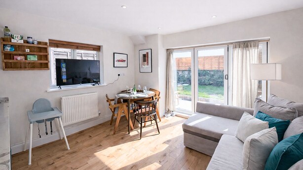 A modern living room with a dining area, a sofa, and a TV. - Queens Park Apt w/ mini garden near Notting Hill (London)