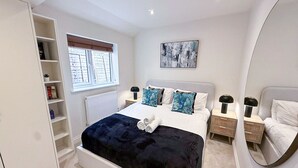 A bedroom with a bed, bedside tables, a wardrobe, a window with blinds, and a painting on the wall. - Queens Park Apt w/ mini garden near Notting Hill (London)