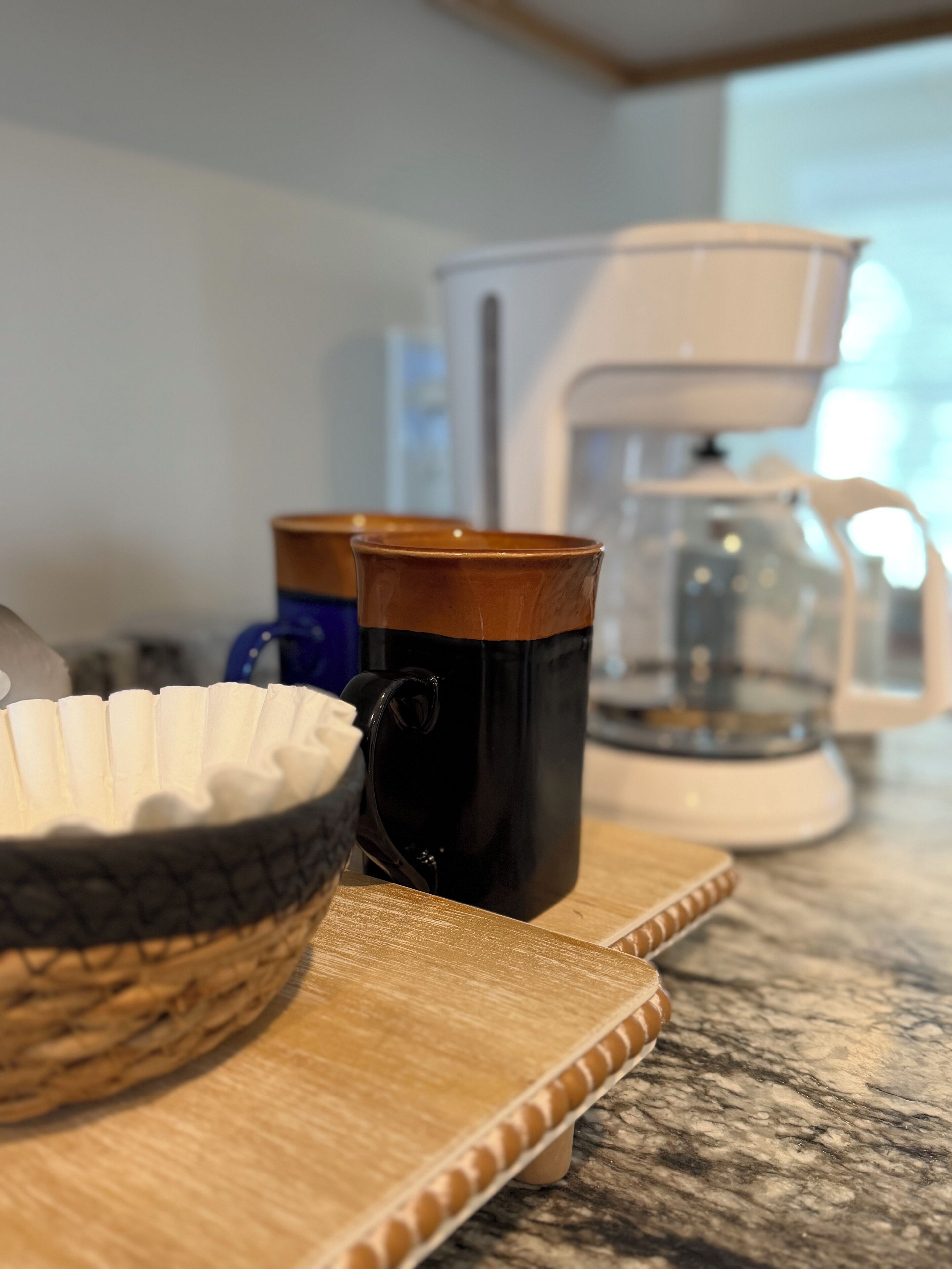 Un comptoir de cuisine avec une machine à café, un bol et deux tasses.
