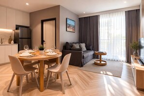 A modern living room with a dining area, a sofa, and a TV. - New Suite 2br the Title Legendary bangtao (Choeng Thale)