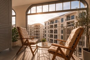 A balcony with two cushioned chairs, a small table, and a potted plant. - NEW Suite 2BR The Title IBG Legendary BangTao (Choeng Thale)