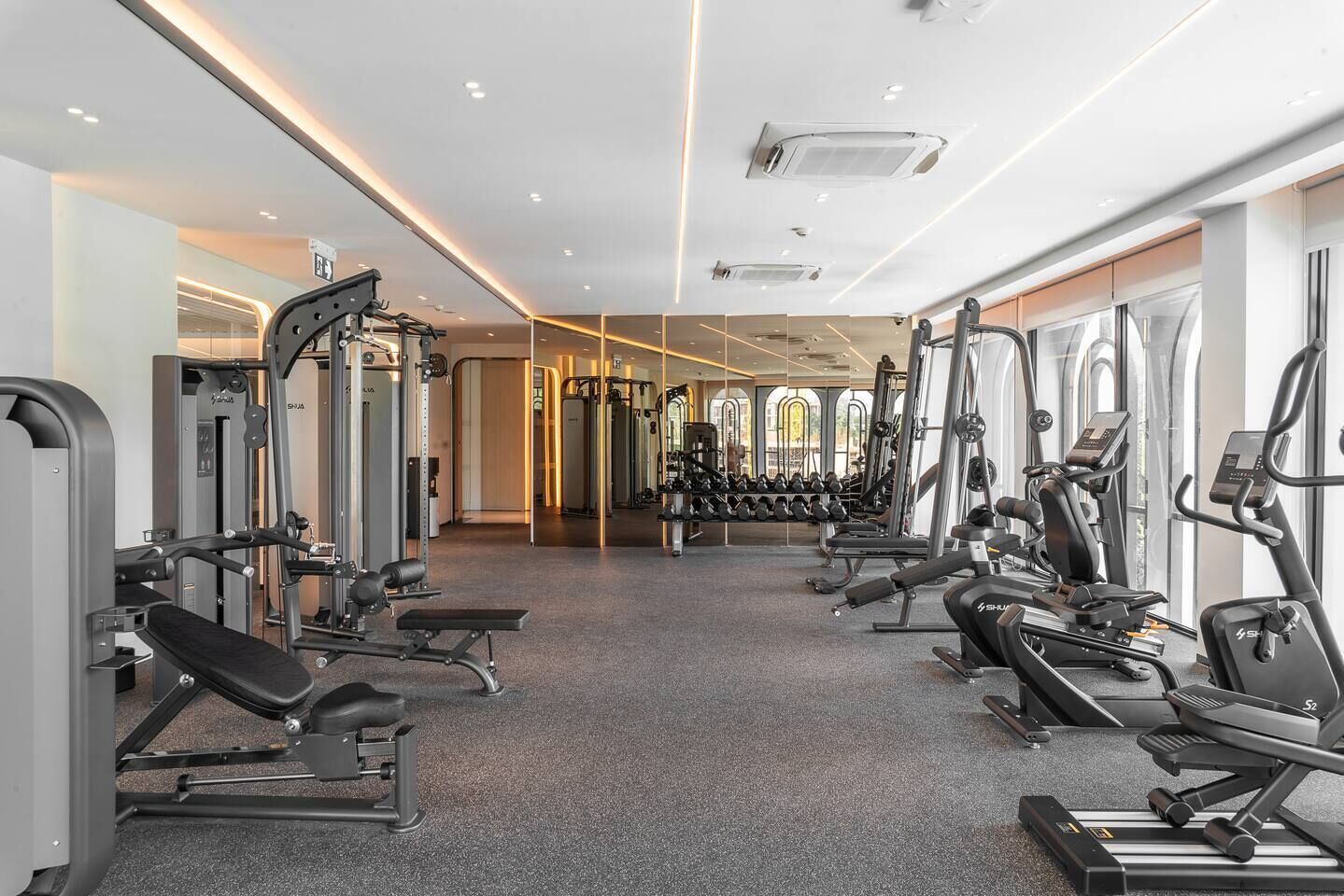 Ein Fitnessstudio mit unterschiedlichen Trainingsgeräten, darunter Laufbänder und Kraftgeräte, in einer großzügigen Anordnung.