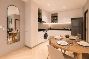 A modern kitchen with a dining area, a washing machine, and a large mirror. - New Suite 2br the Title Legendary bangtao (Choeng Thale)