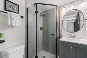 A modern bathroom with a glass-enclosed shower, a white sink, and a large mirror. - Old Town Condo Near CSU | Pool, Sauna, Gym & Bikes (Fort Collins)