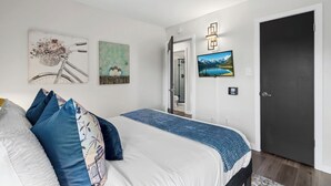 Un dormitorio con cama, almohadas, decoración en la pared, una puerta y un pasillo.
