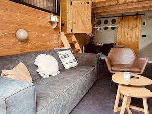Un salon moderne avec un canapé gris, un fauteuil en cuir marron et une petite table en bois.