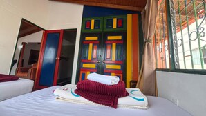 A hotel room with a bed, a colorful door, and a window with metal bars. - Apartamento Zócalos de Guatape (Guatape)