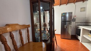 A kitchen with a wooden chair, a glass cabinet, a stainless steel refrigerator, and a stove. - Apartamento Zócalos de Guatape (Guatape)