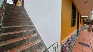 A staircase with red and grey steps leading to a white wall with a yellow door. - Apartamento Zócalos de Guatape (Guatape)