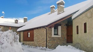 Ein steinernes Gebäude mit schneebedecktem Dach und Schornsteinen, umgeben von Schnee.