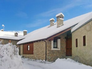 Ein steinernes Gebäude mit schneebedecktem Dach und Schornsteinen, umgeben von Schnee.